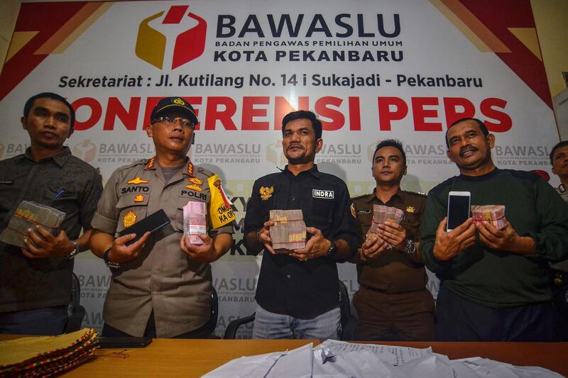 Indonesian police and officers of the Elections Supervisory Agency (Bawaslu) hold seized money, believed to be distributed to influence voters ahead of the upcoming general elections, during a press conference in Pekanbaru, Riau province.