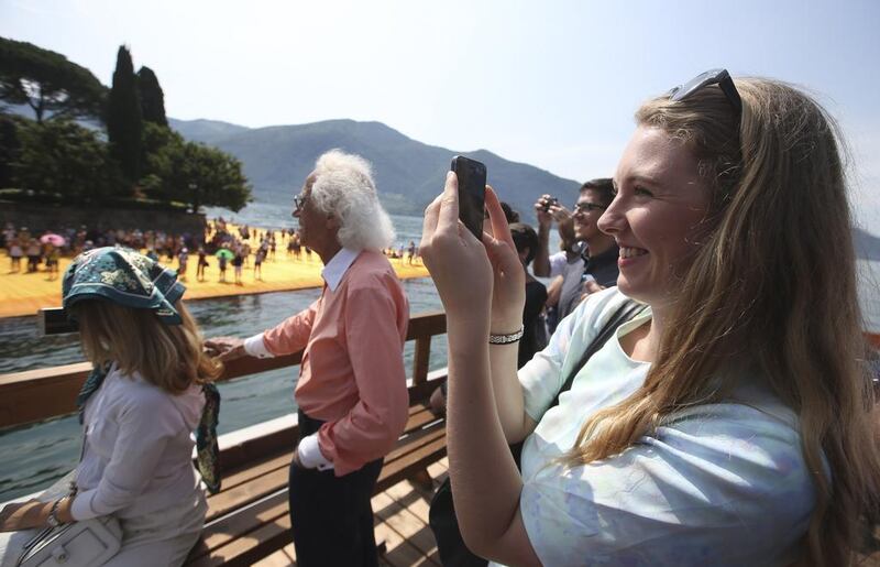 Brittany Trilford takes pictures with her smartphone on a boat sailing around The Floating Piers at the Iseo Lake. Luca Bruno / AP photo