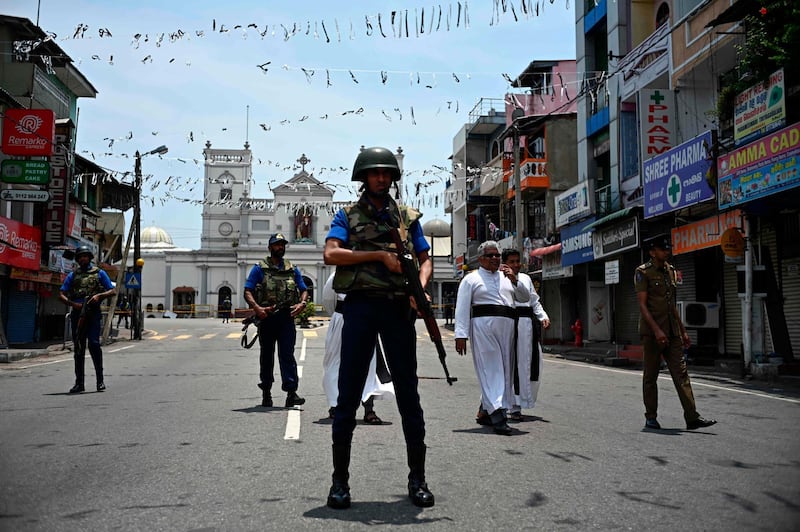 Priests walk on a blocked street as soldiers stand guard outside St. Anthony's Shrine in Colombo on April 25, 2019, following a series of bomb blasts targeting churches and luxury hotels on the Easter Sunday in Sri Lanka. All of Sri Lanka's Catholic churches have been ordered to stay closed and suspend services until security improves after deadly Easter bombings, which killed at least 359 people and wounded hundreds, a senior priest told AFP on April 25. / AFP / Jewel SAMAD
