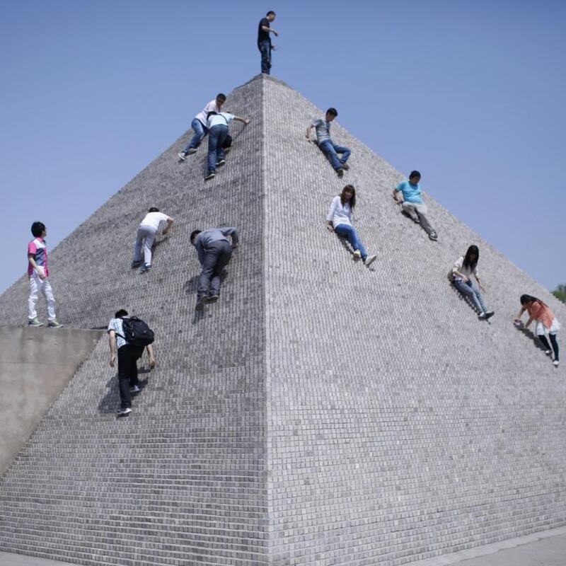 Tourists climb a mini replica of a pyramid in Beijing World Park.