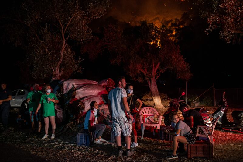 People wait near bushfire in a rural part of Marmaris.