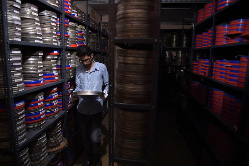 This photograph taken on August 16, 2017 shows an employee taking a film reel to be digitised at the state-run Afghan Film department in Kabul.
When the Taliban knocked on the doors of Afghanistan's film department in the mid-1990s intent on destroying illegal movies, Habibula Ali harboured a secret. He had hidden thousands of reels of footage showcasing Afghanistan's rich cultural history and quivered at the thought of what would happen if the Taliban discovered them. "We did not expect to leave for our homes that day alive," Ali tells AFP, clutching a saved reel. "If they had found out we had hidden movies they would have killed us."
 / AFP PHOTO / SHAH MARAI