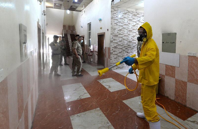 A health worker dressed in protective gear sanitises a local police precinct in the Nabi Yunus district of Iraq's northern city of Mosul on May 28, 2020, due to the COVID-19 coronavirus pandemic.  / AFP / Zaid AL-OBEIDI
