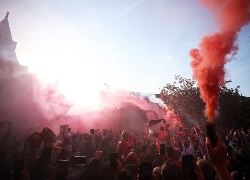 Liverpool fans hold flares outside the stadium as the team coach arrives. Reuters