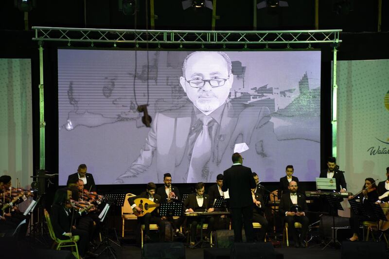 Images of famous Iraqi cultural and art personalities are shown on a screen during the concert by the Watar orchestra. EPA