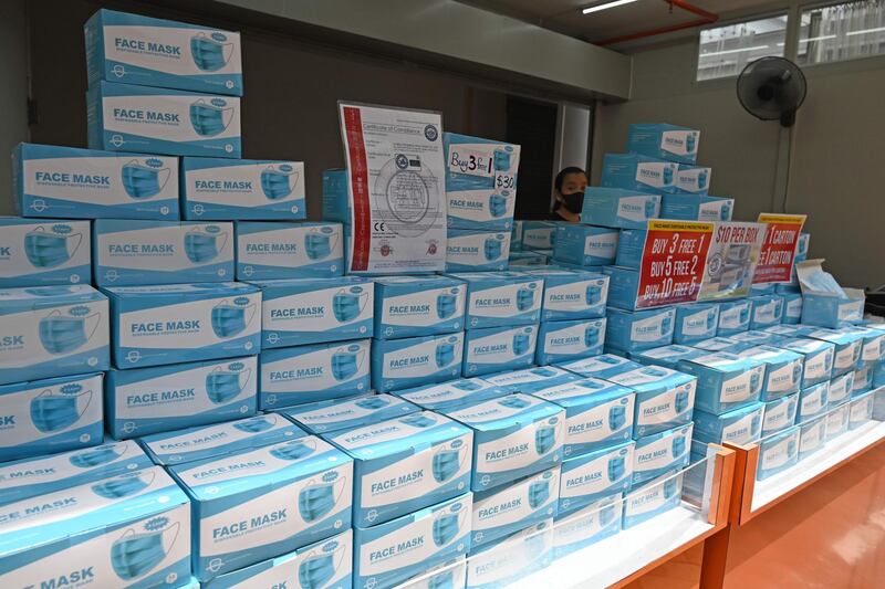 A vendor stands behind stacks of face masks in boxes for sale in Singapore. AFP