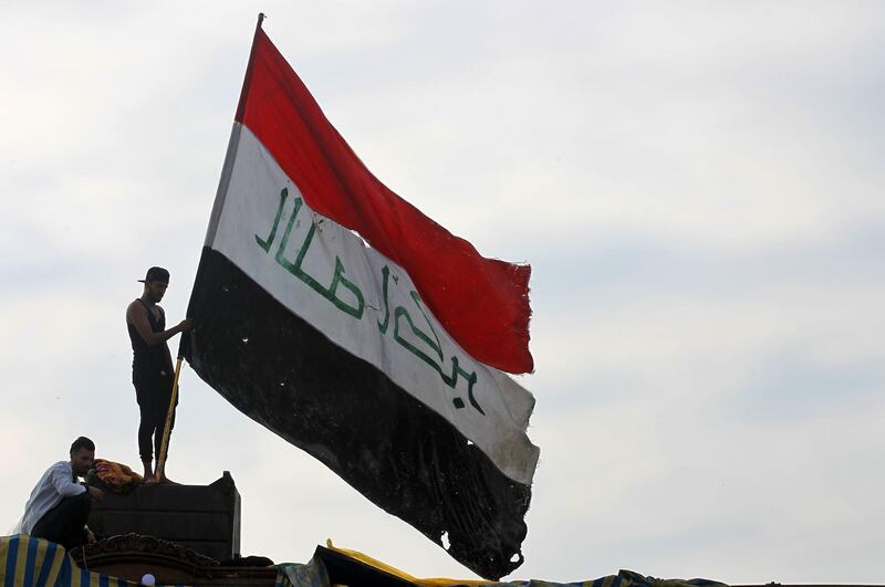 TOPSHOT - An Iraqi demonstrator waves a large national flag in the capital Baghdad's Tahrir Square, amid ongoing anti-government protests, on December 6, 2019.  Tahrir has become a melting pot of Iraqi society, occupied day and night by thousands of demonstrators angry with the political system in place since the aftermath of the US-led invasion of 2003 and Iran's role in propping it up. / AFP / AHMAD AL-RUBAYE
