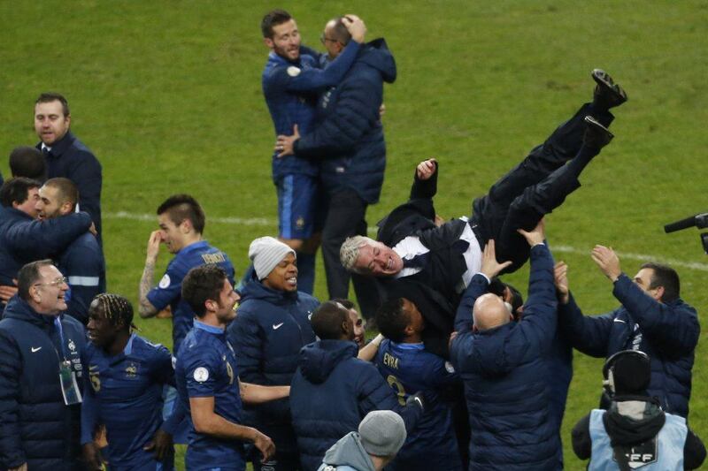 The French squad lift Didier Deschamps into the air following their World Cup qualification on Tuesday night. Thibault Camus / AP