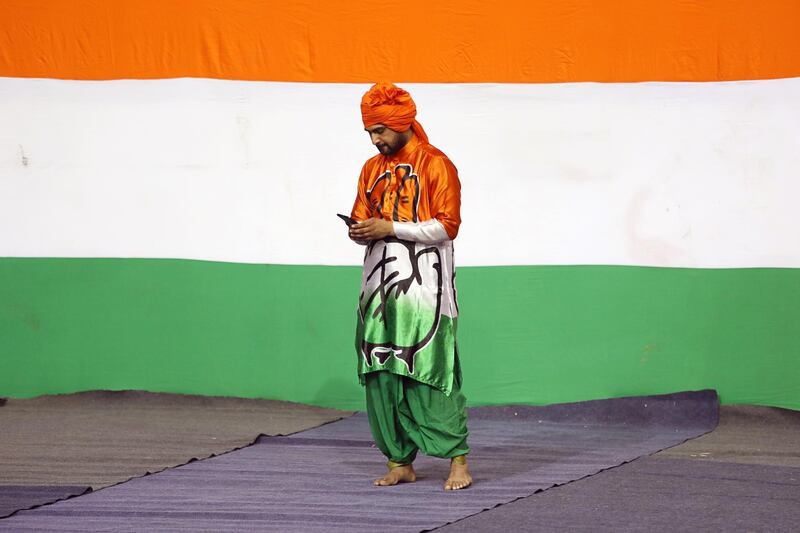 An attendee wearing clothing featuring the Indian National Congress party logo uses a mobile phone at an event in New Delhi, India. Bloomberg