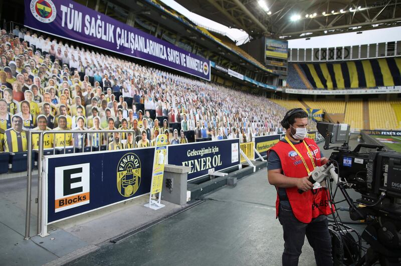 A TV cameraman stands in front of cardboard cutouts of Fenerbahce fans in the stands prior to the club's Turkish Super League football match against Kayserispor in Istanbul. AP