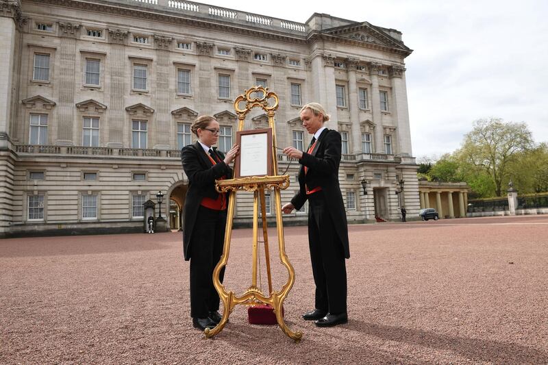 Senior footman Olivia Smith and footman Heather McDonald place a notice on an easel in the forecourt of Buckingham Palace to formally announce the birth of a baby boy to the Britain's Catherine, the Duchess of Cambridge, and Prince William, in London, April 23, 2018. (Stefan Rousseau/ Reuters)