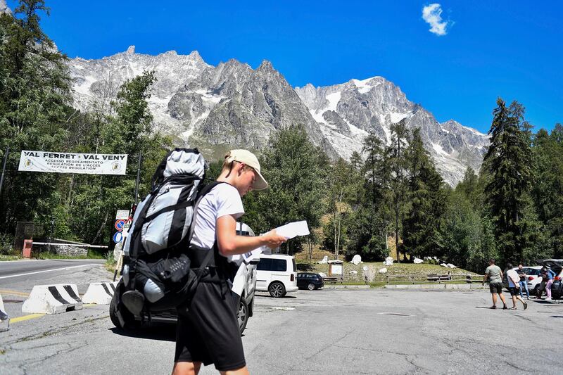 A hiker looks at a map as he walks in a parking lot beneath the Planpincieux glacier. AP