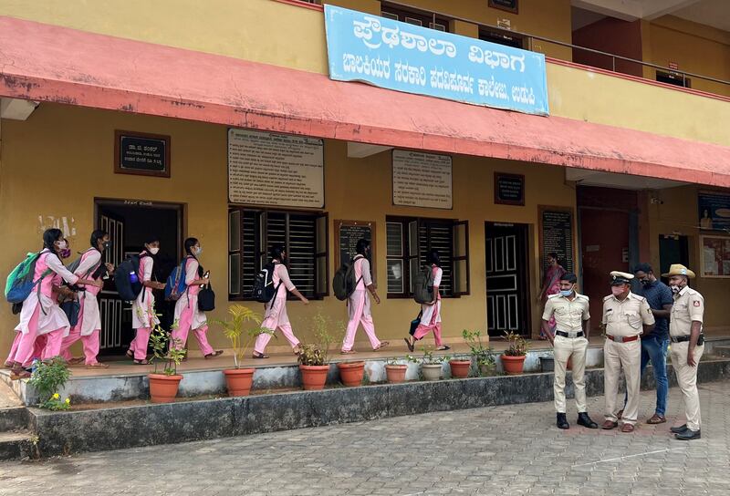 Indian police officers stand outside a government girls school in Udupi, Karnataka, as pupils arrive for class on February 14, 2022. Reuters