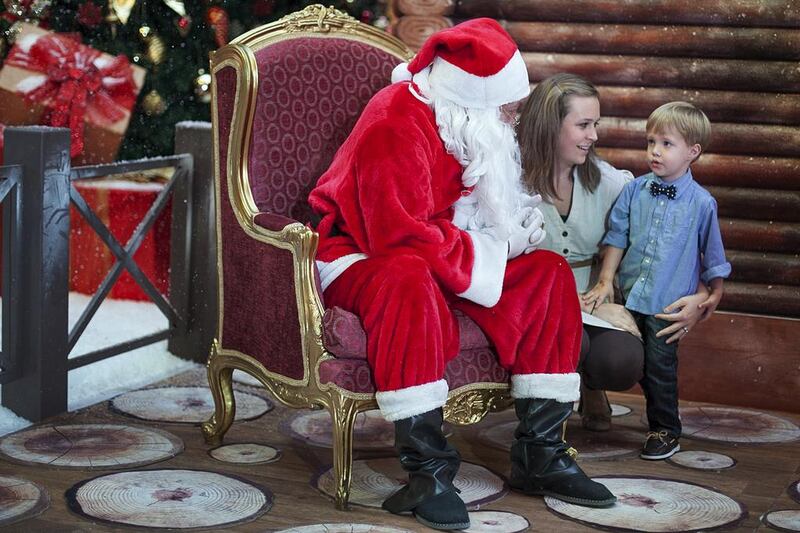 Michelle Gallman, from Savannah, Georgia, persuades her son, Braxton, 3, to get himself pictured with Santa Claus. Mona Al Marzooqi / The National