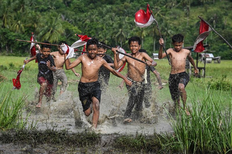 Boys carrying Indonesian flags run through a field in Nusa tourism village, Aceh province, on the eve of the country's 78th Independence Day. AFP
