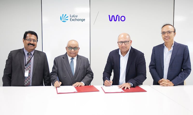 Richard Wason, chief executive of LuLu Exchange, centre left, and Prateek Vahie, chief commercial officer of Wio Bank, centre right, sign the agreement to activate Lulu Exchange branches as service enablement centres for Wio Business customers. Photo: Lulu Exchange and Wio Bank