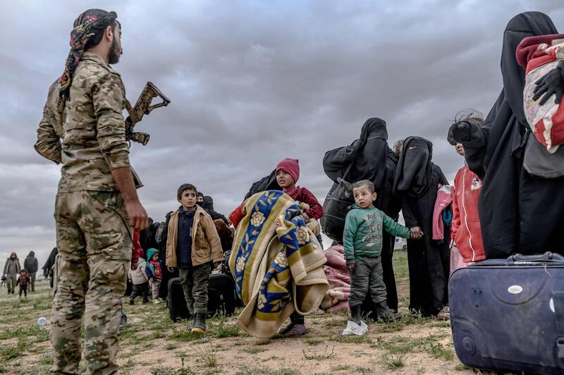 In this photo taken on February 27, 2019, young children look at a member of the Kurdish-led Syrian Democratic Forces after leaving ISIS's last holdout of Baghouz, in Syria's northern Deir Ezzor province. AFP