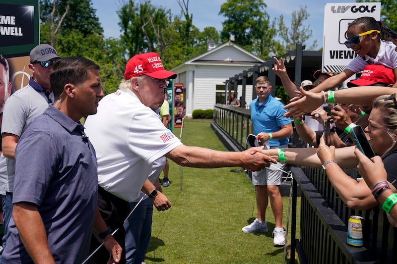 Mr Trump shakes hands with fans. AP