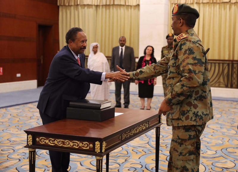 epa07784903 Sudan's new Prime Minister Abdalla Hamdok (L) shakes hands with Abdel Fattah Abdelrahman Burhan (R) after being sworn in during a ceremony at the presidential palace in Khartoum, Sudan, 21 August 2019. The Sudanese opposition and military council signed on 17 August a power sharing agreement. The agreement sets up a sovereign council made of five generals and six civilians, to rule the country until general elections. Protests had erupted in Sudan in December 2018, culminating in a long sit-in outside the army headquarters which ended with more than one hundred people being killed and others injured. Sudanese President Omar Hassan al-Bashir stepped down on 11 April 2019.  EPA/MARWAN ALI