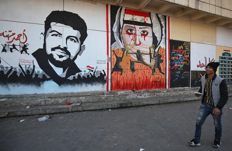 Iraq demonstrators walk past graffiti at Tahrir square in central Baghdad.  AFP