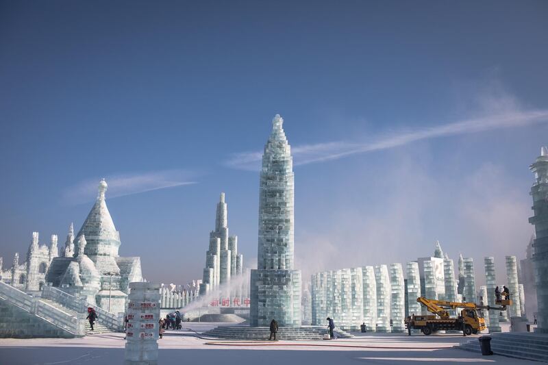 Workers use a machine to blow snow on the ice sculptures and perform other preparations. EPA