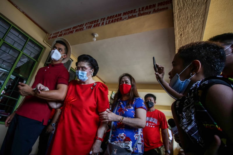 Imelda Marcos, mother of the Philippines presidential candidate Ferdinand Marcos Jr, is led through a polling station during the election in Batac, Ilocos Norte. AFP