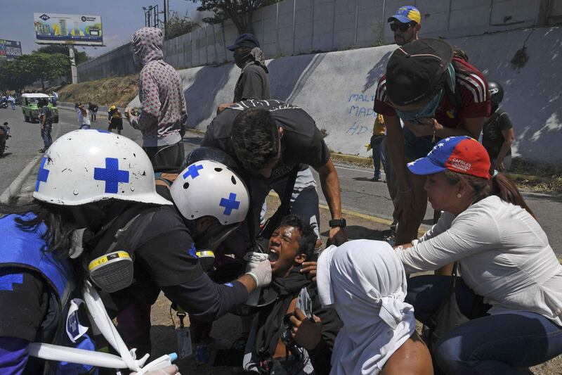 An opposition demonstrator affected by tear gas is assisted during clashes with soldiers loyal to Mr. Maduro. AFP