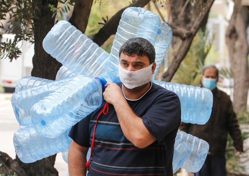 A man covers his face with a makeshift mask as he carries empty gallons of water, during a lockdown to prevent the spread of coronavirus disease in Beirut, Lebanon. Reuters