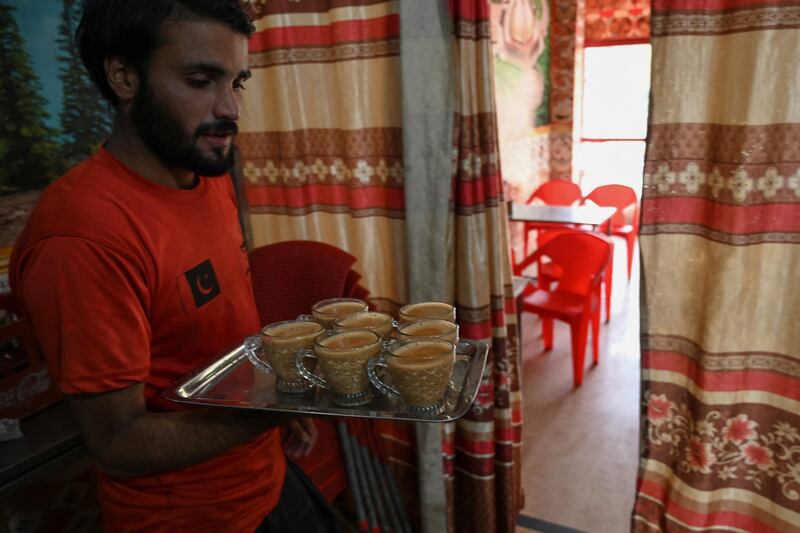 A waiter holds a tray with cups of tea for customers at a restaurant in Islamabad. AFP