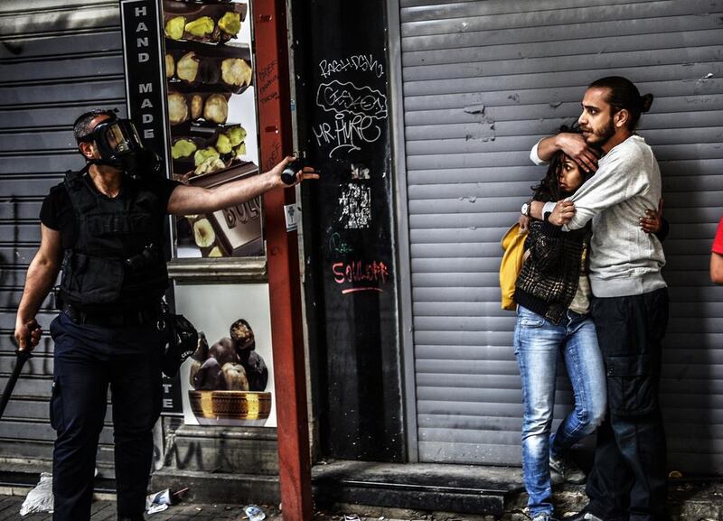 A man protects a woman as they face a police officer dispersing protesters who gathered on the central Istoklal avenue near Taksim square in Istanbul as the police blocked access to the square during the one year anniversary of the Gezi park and Taksim square demonstrations. Bulent Kilic / AFP