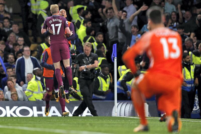Chelsea's Belgian goalkeeper Thibaut Courtois (R) looks on as Manchester City's Belgian midfielder Kevin De Bruyne celebrates with teammates after scoring the opening goal of the English Premier League football match between Chelsea and Manchester City at Stamford Bridge in London on September 30, 2017. / AFP PHOTO / Adrian DENNIS / RESTRICTED TO EDITORIAL USE. No use with unauthorized audio, video, data, fixture lists, club/league logos or 'live' services. Online in-match use limited to 75 images, no video emulation. No use in betting, games or single club/league/player publications.  / 