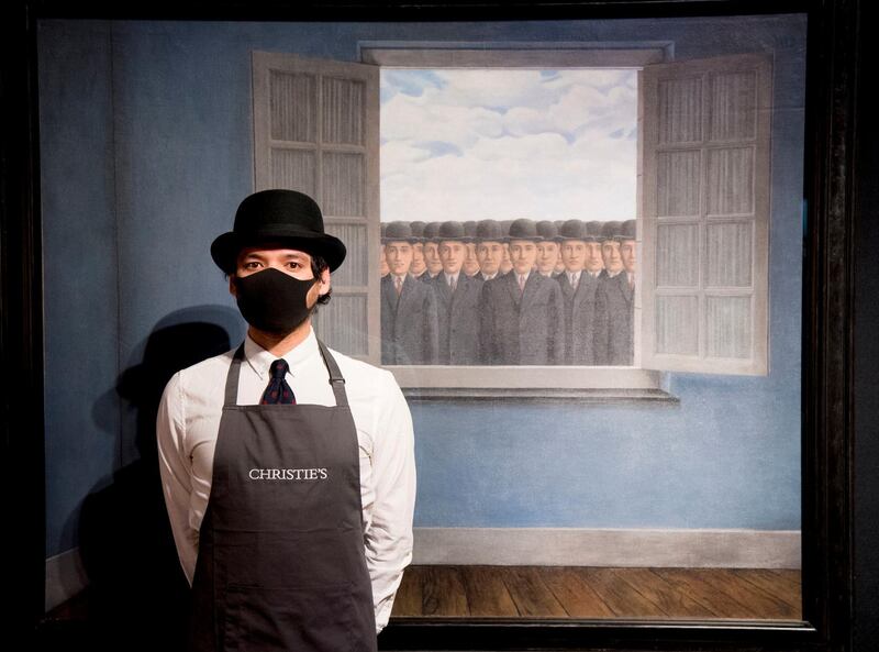 An employee of Christie's auction house in London, England, stands by Magritte's artwork 'Le Mois des Vendanges', which has a value estimate of £10 million to £15m ($14m to $21m). Christie's forthcoming 20th Century Art sale will include works from Picasso and Magritte, among others. AP