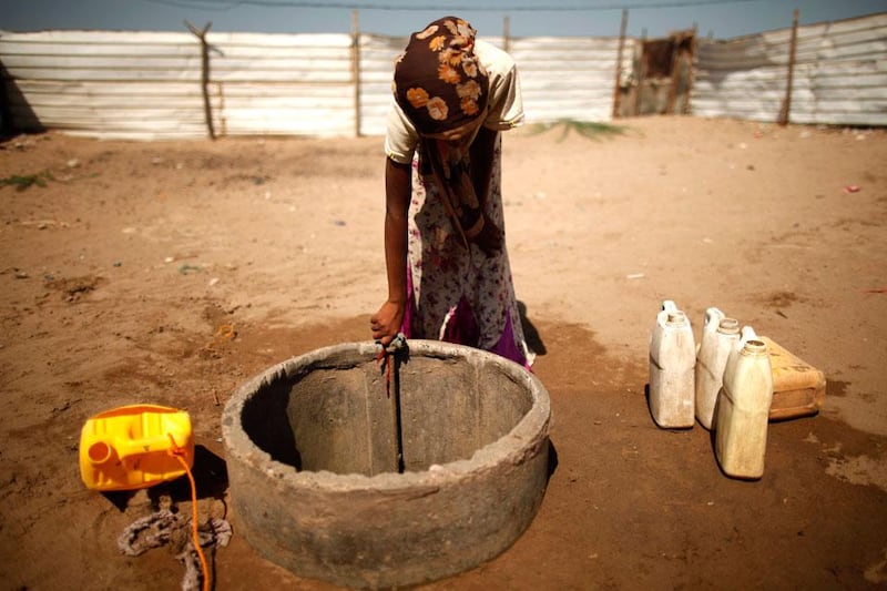A girl collects water from a makeshift well in the Akhdam community in Houdieda.