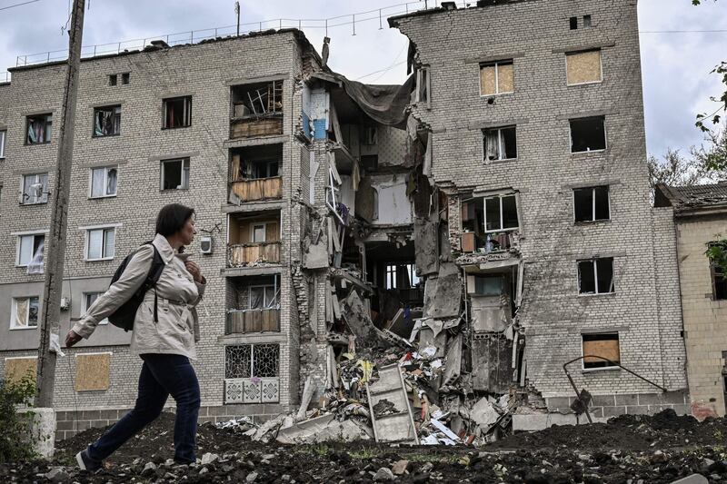A woman walks by a destroyed apartment building in Bakhmut, Donbas region. AFP