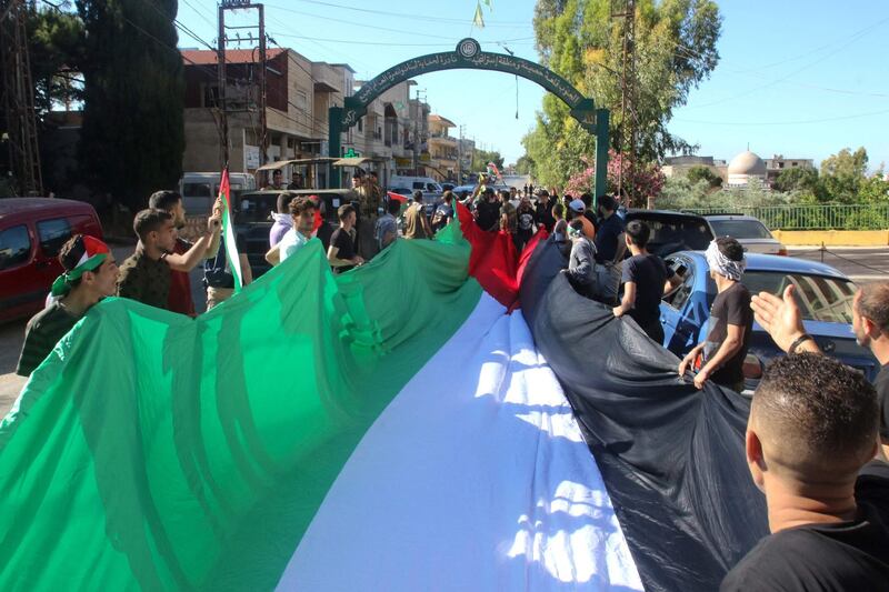 Pro-Palestinian protesters march with a large flag during a rally in the southern Lebanese village of Adaisseh, marking the Nakba and denouncing Israeli violence in Gaza and Jerusalem. AFP