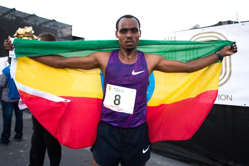 Legese celebrates his win with the Ethiopian flag draped on his shoulders.