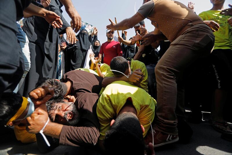 Demonstrators play the role of detainees as they gather to mark the first anniversary of the anti-government protests at Tahrir Square in Baghdad. Reuters