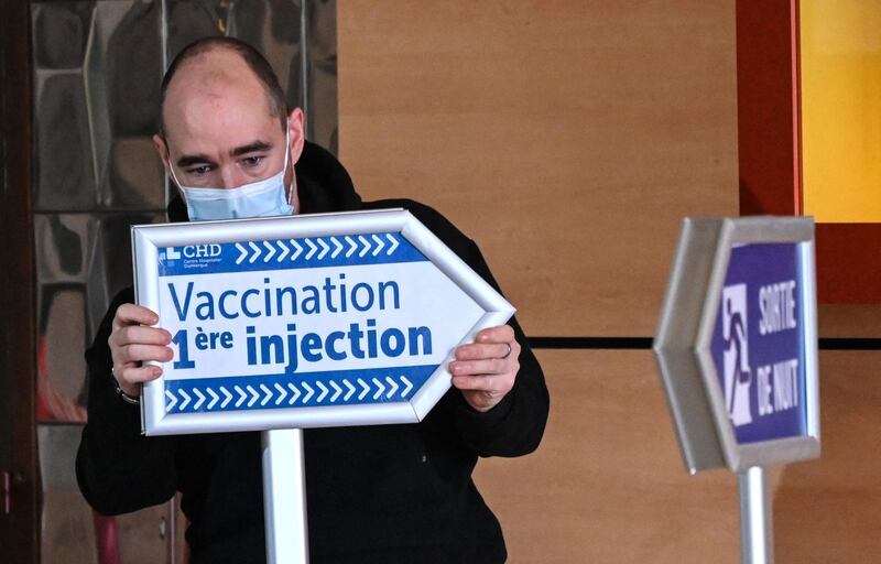 An employee at the Dunkirk Hospital Center sets-up signs to guide patients arriving to be administered with the Covid-19 vaccine. AFP