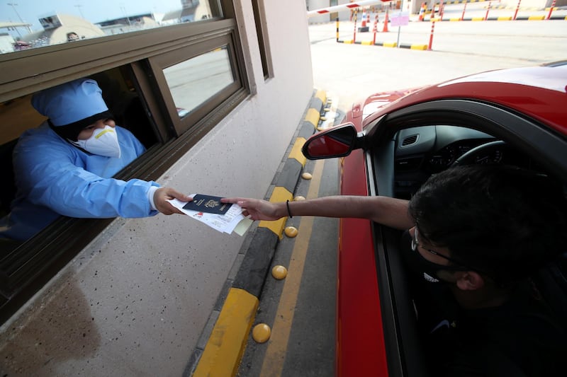 A medical inspector hands documents back to an American national in a car as he crosses from Saudi Arabia into Bahrain at an immigration checkpoint on the King Fahd Causeway that reopened after coronavirus disease (COVID-19) restrictions were eased, at the Bahrain-Saudi border, Bahrain, September 15, 2020. REUTERS/Hamad I Mohammed