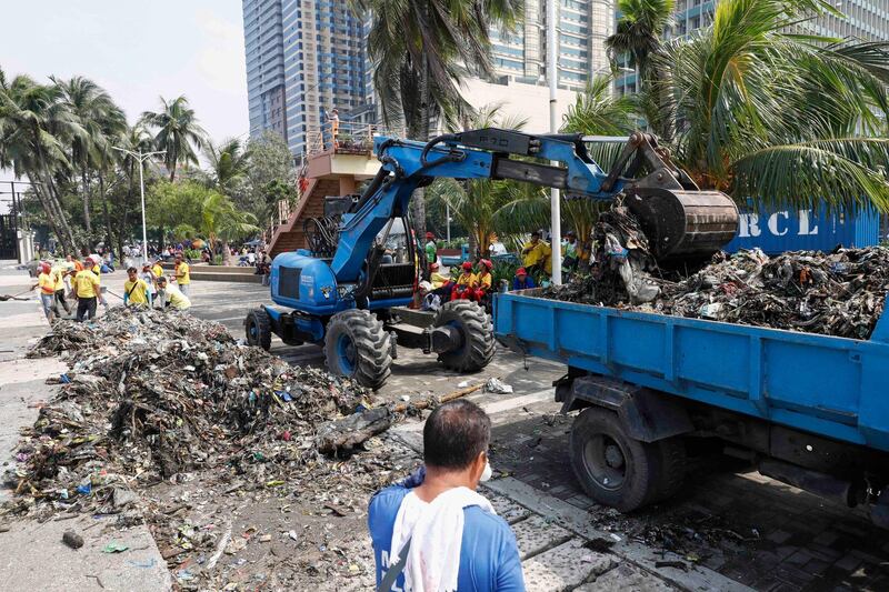 Government workers collect trash and debris along the shore of Manila Bay as part of typhoon precautions in Manila. EPA