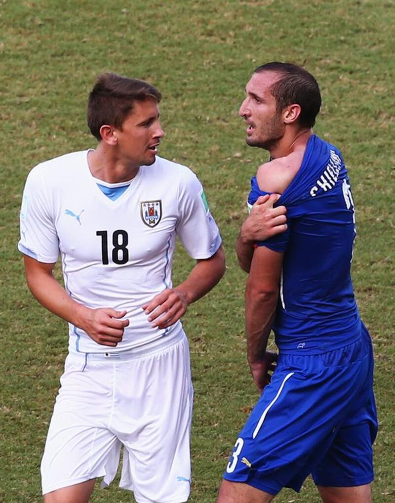 Giorgio Chiellini of Italy pulls down his shirt after a clash to show off his shoulder, appearing to claim Luis Suarez of Uruguay, not pictured, had bitten him on Tuesday at the 2014 World Cup. To the left, Gaston Ramirez of Uruguay. Julian Finney / Getty Images  