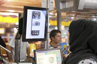 Cashier in a World Food Programme-run supermarket in Zaatari refugee camp verifies a payment using the iris-scan method. Courtesy WFP / Mohammad Batah