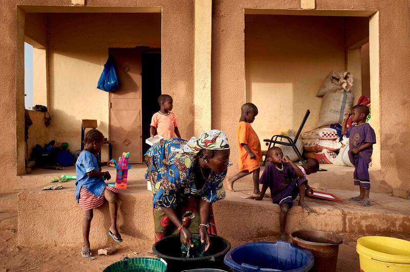 A displaced woman does the laundry while a group of children is playing behind here, in Sevare in central Mali on February 26, 2020. AFP