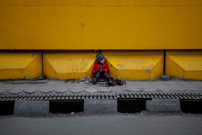 A young shoe-shiner sits as he waits for customers alongside a street in Kabul. AFP