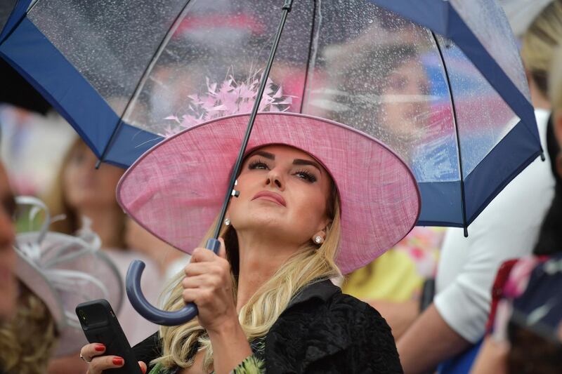 This racegoer protects her delicate blush hat from the very British weather.AFP
