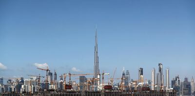 TOPSHOT - A general view of cranes at a construction site with the world's tallest tower Burj Khalifa (background) in the Gulf emirate of Dubai on March 11, 2019. / AFP / KARIM SAHIB
