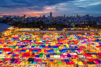 Night scene of colorful tent and cityscape at Chatujak market secondhand market in Bangkok , Thailand. Getty Images