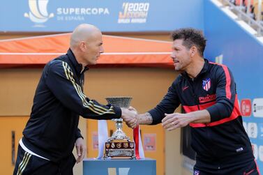 Real Madrid manager Zinedine Zidane, left, and Atletico Madrid manager Diego Simeone shake hands in front of the Spanish Super Cup trophy. AP Photo