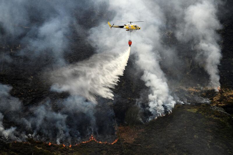 A helicopter drops water taken from a nearby reservoir onto flames after a resurgence of the fire on Marsden Moor, near Huddersfield, northern England. AFP