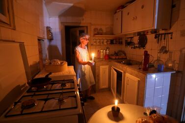 Samira Hanna, 70, holds a candle as she walks in her kitchen during a power cut in Beirut. Reuters